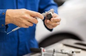 Tehnician verificând o piesă auto cu șublerul